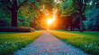 park path leads towards a setting sun, with trees, green grass, and flowers on a peaceful evening