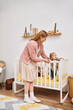 © LIGHTFIELD STUDIOS - joyful woman supporting little son standing in crib in nursery room at home, happy motherhood