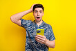 Photo of speechless man with bristle dressed blue clothes hold smartphone arm on head read comment isolated on yellow color background