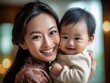 © Tamazina - Young asian woman holding her baby in her arms.