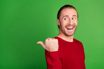 Wall Mural - Portrait of funny guy with long hairstyle wear red sweatshirt look indicating at sale empty space isolated on green color background