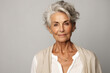 © FoxTok - Portrait of chic beautiful gray-haired mature woman 50-60 years old in elegant clothes on gray background. An elderly woman smiles and looks at camera. Beautiful old age, cosmetology, face lifting