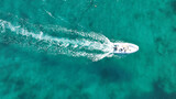 Fototapeta Na drzwi - Aerial drone top down photo of small inflatable rib speed boat cruising in high speed deep emerald sea of Mykonos island, Cyclades, Greece