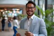 © olegganko - A cheerful young Latin business executive holding a tablet in the office