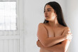 latina woman covering her breasts with her hands while looking to the side, on a white background