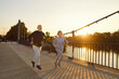 © Studio Romantic - Happy healthy elderly couple enjoying a jogging workout on a sunny summer evening. Old man and woman in sportswear running together along a concrete bridge in the city park. Sport concept