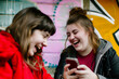 © Adrian - Two teenage girls in the street with a mobile phone in their hands