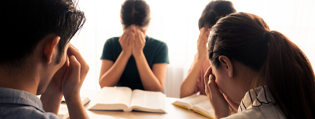 Cropped image of Group of believer hand praying together while raising hand at wooden church on bible book. Prayers hold hand together faithfully. Concept of hope, religion, faith, god blessing