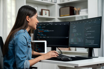 Young Asian in IT developer creating with typing online information on pc with coding program data of website application, wearing jeans shirt. surrounded by safety analysis two screens. Stratagem.