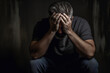 © AspctStyle - Distressed Man Sitting with Hands on Head in Dark Room. Mental Health and Despair Concept