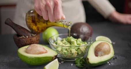 Sticker - Woman pouring cooking olive oil onto Chopped avocado in glass bowl at domestic kitchen