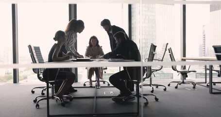 Poster - Multiethnic project team working on paper marketing reports together, analyzing statistic data, reviewing documents, bending over table, discussing strategy, brainstorming on plan. Through glass view