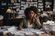 A worried black woman doing financial planning surrounded by lots of paper.