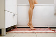 © boomeart - Leg of unrecognizable woman on a carpet near bathtub