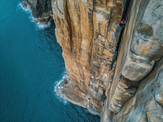 Drone shot of rock climbers scaling a sheer cliff face