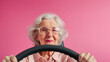 Photo portrait of lovely senior lady hold steering wheel driving lesson wear trendy garment isolated on pink color background. Senior women driver