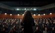 Backview of female brunette long curly hair motivational speaker in front of her conference meeting audience