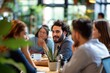 © Zireael - Focused shot of a young man in a social setting, surrounded by colleagues, engaging in a lively discussion at a modern café with a warm and inviting atmosphere.
