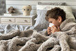 petit garçon brun, dans son lit sous les couvertures, en train de se moucher car il est malade ou allergique. Rhume, Grippe, Coronavirus, COVID-19
