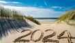 Nordsee Urlaub 2024 in den Sand am Strand geschrieben mit Dünen im Hintergrund