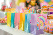 Colorful goodie bags lined up on a table, filled with treats and small toys, bright and festive setting with party decorations in the background