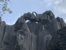 AI Generated Illustration Of A Towering Rock Formation With A Petite Archway At Its Peak