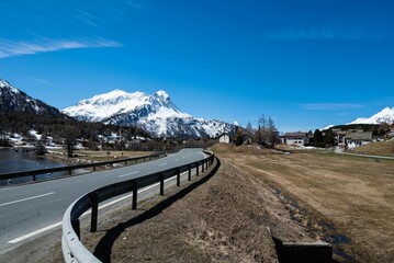 Wall Mural - a curve road passes by a mountain with some snow capped peaks