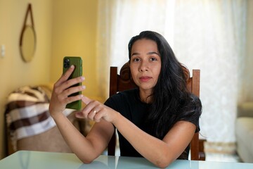 a young woman holding her cell phone in front of a bed