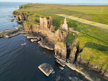 Aerial View Of The Historic Sinclair Girnigoe Castle Ruins On A Rocky Outcrop At Sunset