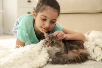 Wall Mural - Cute little girl with cat lying on carpet at home. First pet