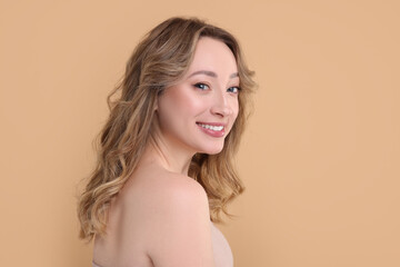 Wall Mural - Portrait of smiling woman on beige background