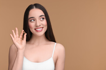 Wall Mural - Beautiful young woman with vitamin pill on beige background. Space for text