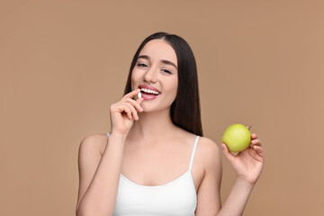 Poster - Beautiful young woman with vitamin pill and apple on beige background