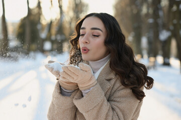 Canvas Print - Portrait of beautiful woman blowing snow from hands in park