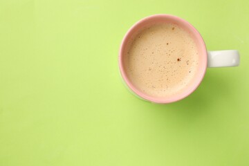 Poster - Aromatic coffee in cup on light green background, top view. Space for text