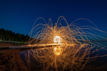 Wall Mural - Night scene featuring a burning fire created by spinning steel wool with a long exposure.