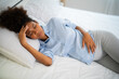Top view of Young African American pregnant woman lay on bed, have an head ache with eye bow fold together, pregnant lady sick lay on bed. Taking care, and health concept.