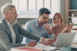 © gstockstudio - Three confident business people having discussion while working in the office together