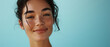 Effortless beauty, a young woman with sun-kissed freckles gives a subtle smile against a serene turquoise backdrop