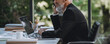 © gstockstudio - Confident mature businessman talking on mobile phone while sitting sat his working place in office