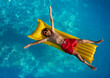 Relaxed swimmer afloat in pool on a yellow raft view from above