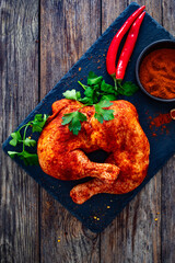 Wall Mural - Raw seasoned chicken thighs on stony cutting board on wooden table
