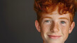 Closeup portrait of a young teenage boy, male teenager with redhead foxy hair and ginger freckles on his face or skin, looking at the camera and smiling, studio shot. One happy model