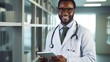 © liliyabatyrova - A happy African male doctor with a tablet in his hands in the hospital. Healthcare, Medicine, Science concepts.