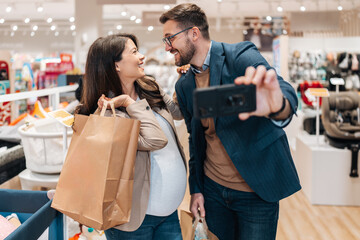 Wall Mural - Satisfied and happy couple leaves a baby store with shopping bags. Parenthood and child expecting concept.