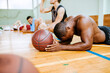 © Marko Geber - Young people taking a break from playing basketball in an indoor basketball gym