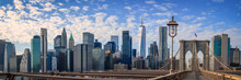 New York City Manhattan Skyline Over The Brooklyn Bridge, Skyscrapers, The Landmark Gothic-Revival Massive Granite Towers, And Wooden Footpath Over The East River In New York