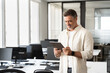 © Stock 4 You - Happy Latin Hispanic bearded stylish mature adult professional business man, smiling Indian senior businessman CEO holding digital tablet using fintech tab application standing inside company office.