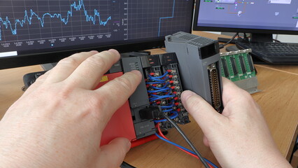 Wall Mural - an electrical engineer adds a new io card to a modular plc automaton. programmable logic controller.