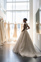 In the preparation for the wedding, a stylish and elegant black bride chooses a beautiful white dress in a luxurious bridal shop.